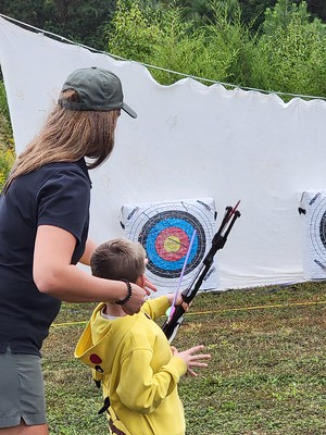 Ranger teaching kid to shoot a bow.